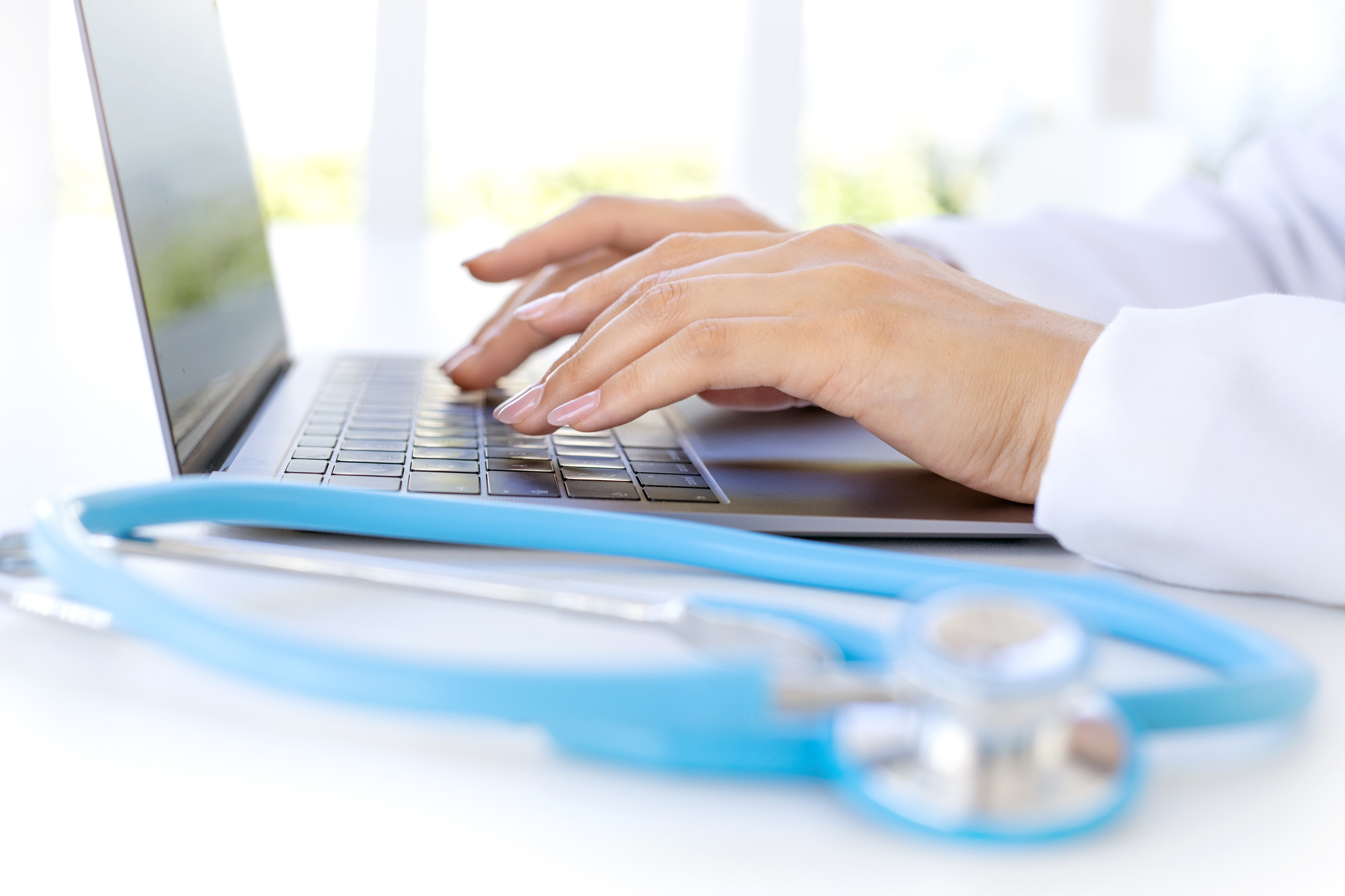 close up di un medico donna che scrive sulla tastiera del suo laptop